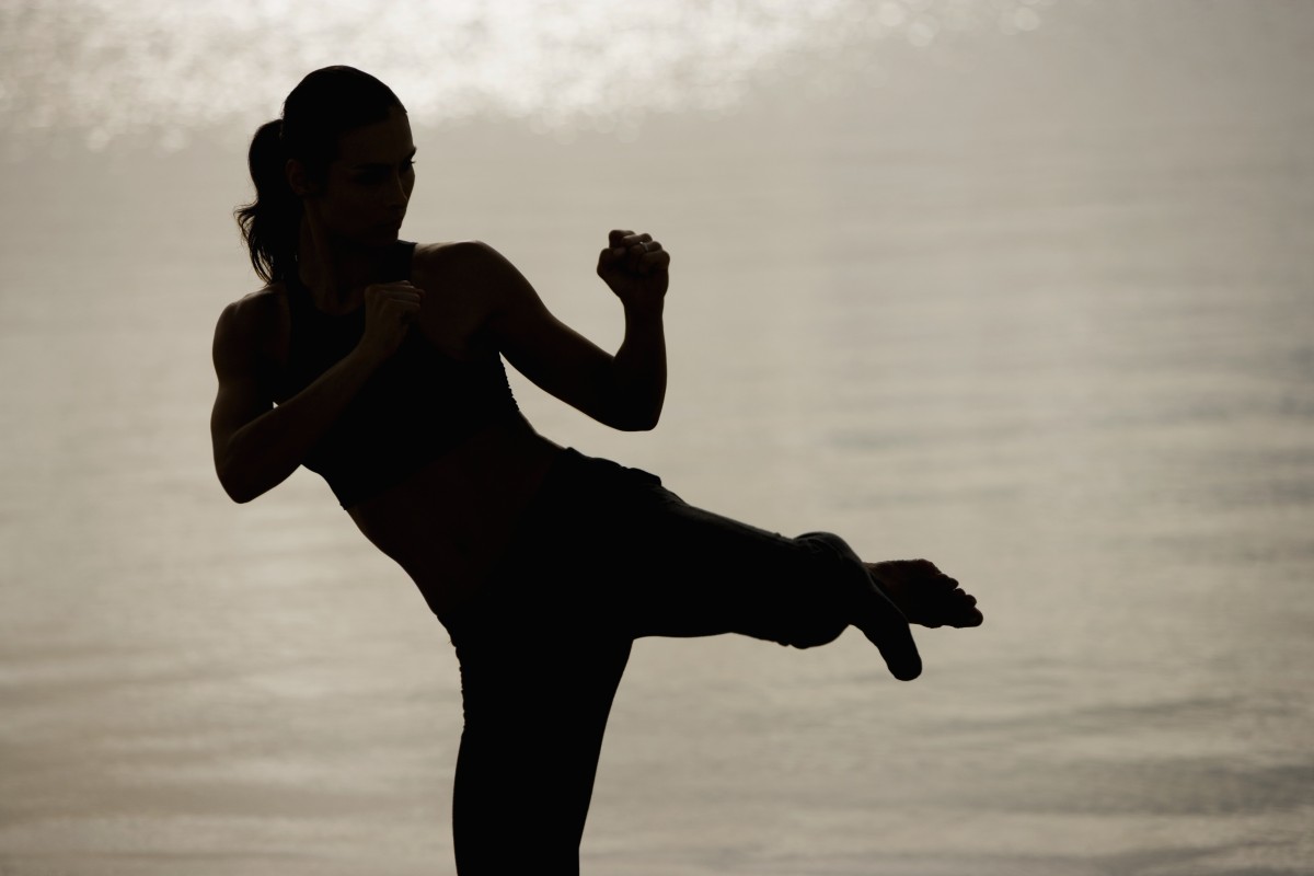 Silhouette of a young woman practicing martial arts on the beach